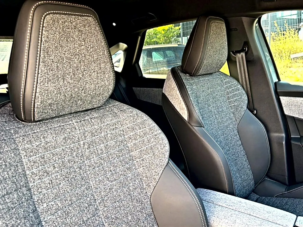 Gros plan sur les sièges avant tissu gris et cuir noir du Peugeot 3008 1.2 Hybrid 145 Allure 2025, côté conducteur et passager.