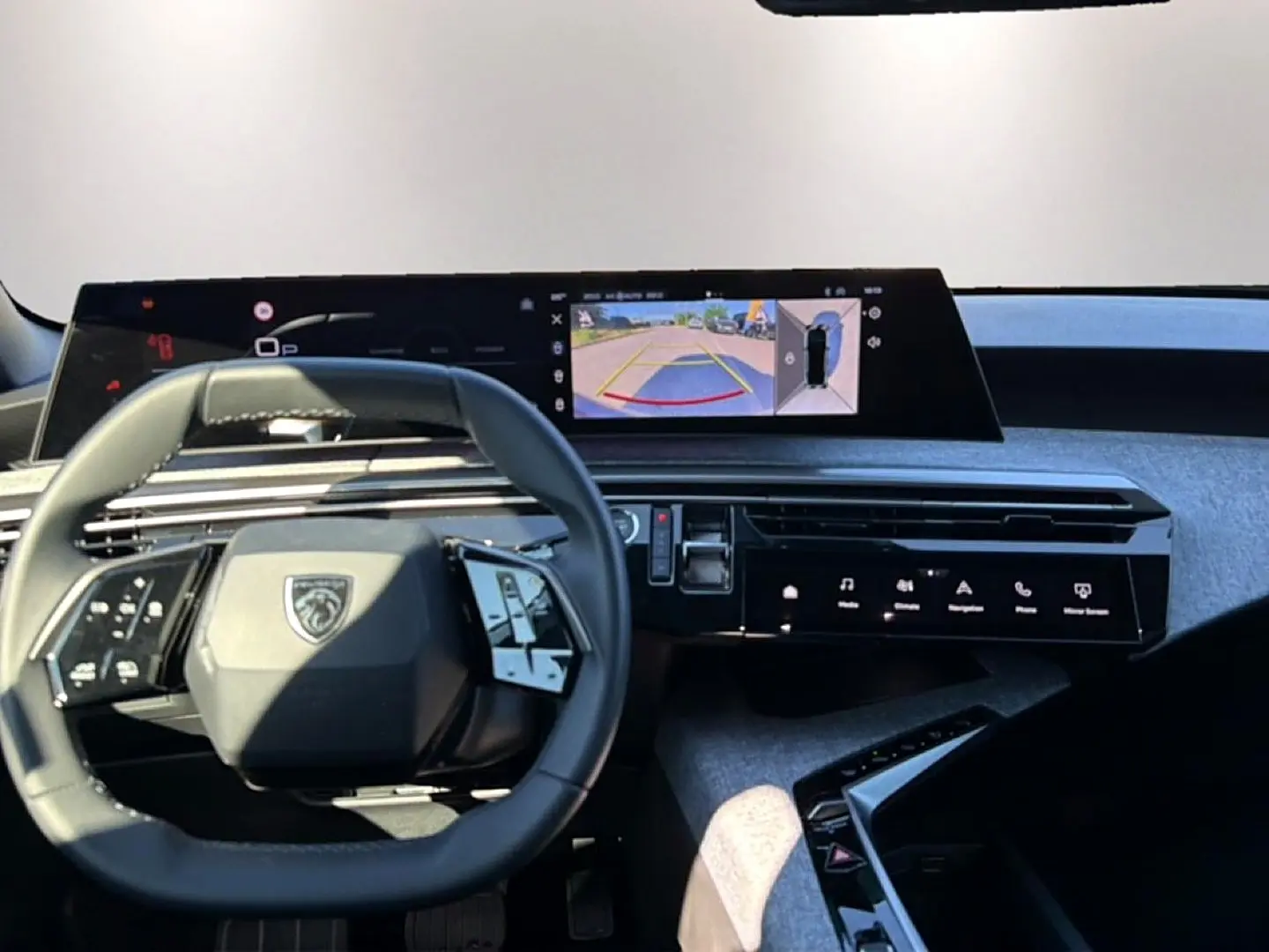 Vue intérieure du tableau de bord du Peugeot 3008 bleu Ingara 2025, avec volant multifonction et écran tactile central affichant la caméra de recul.