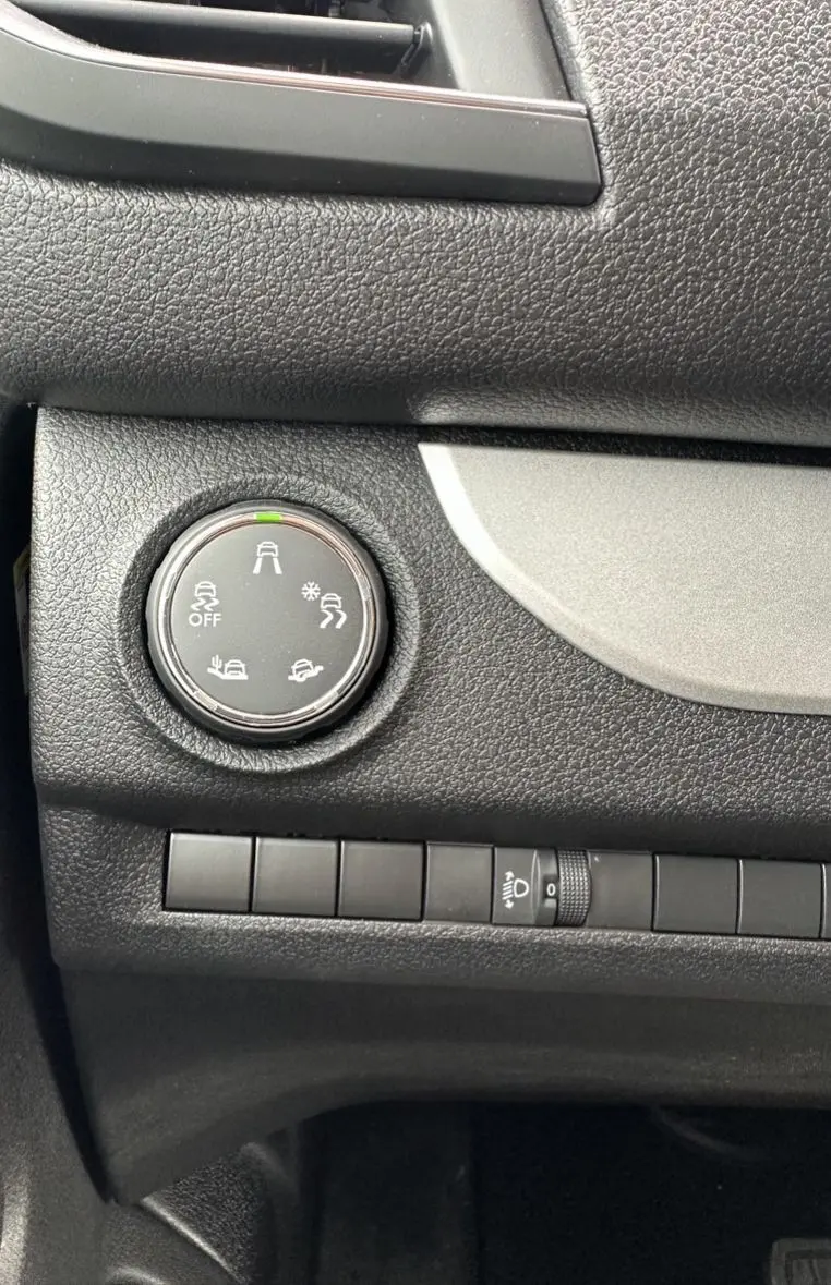 Gros plan sur le bouton de sélection des modes de conduite du tableau de bord noir du Citroën Jumpy van blanc électrique.