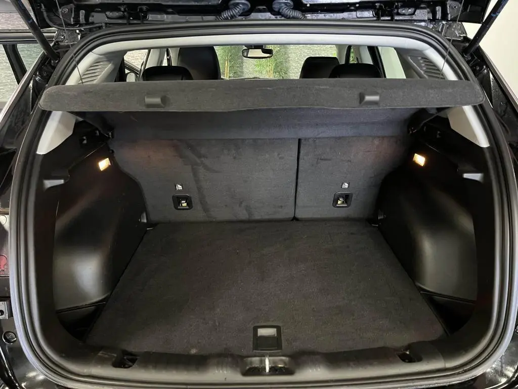 Coffre ouvert du Jeep Compass noir 2024, vue arrière montrant l'espace de chargement avec cache-bagages et éclairage intérieur.
