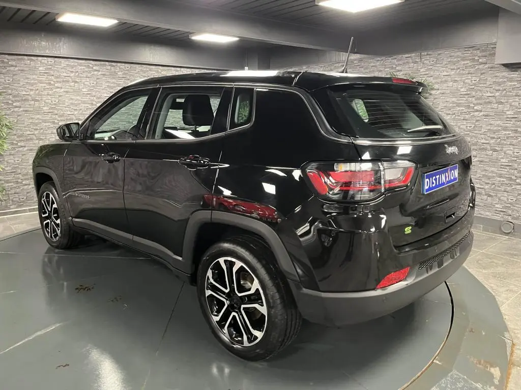 Jeep Compass noir en 3/4 arrière droit, jantes alliage noires et argent, dans un showroom intérieur moderne.