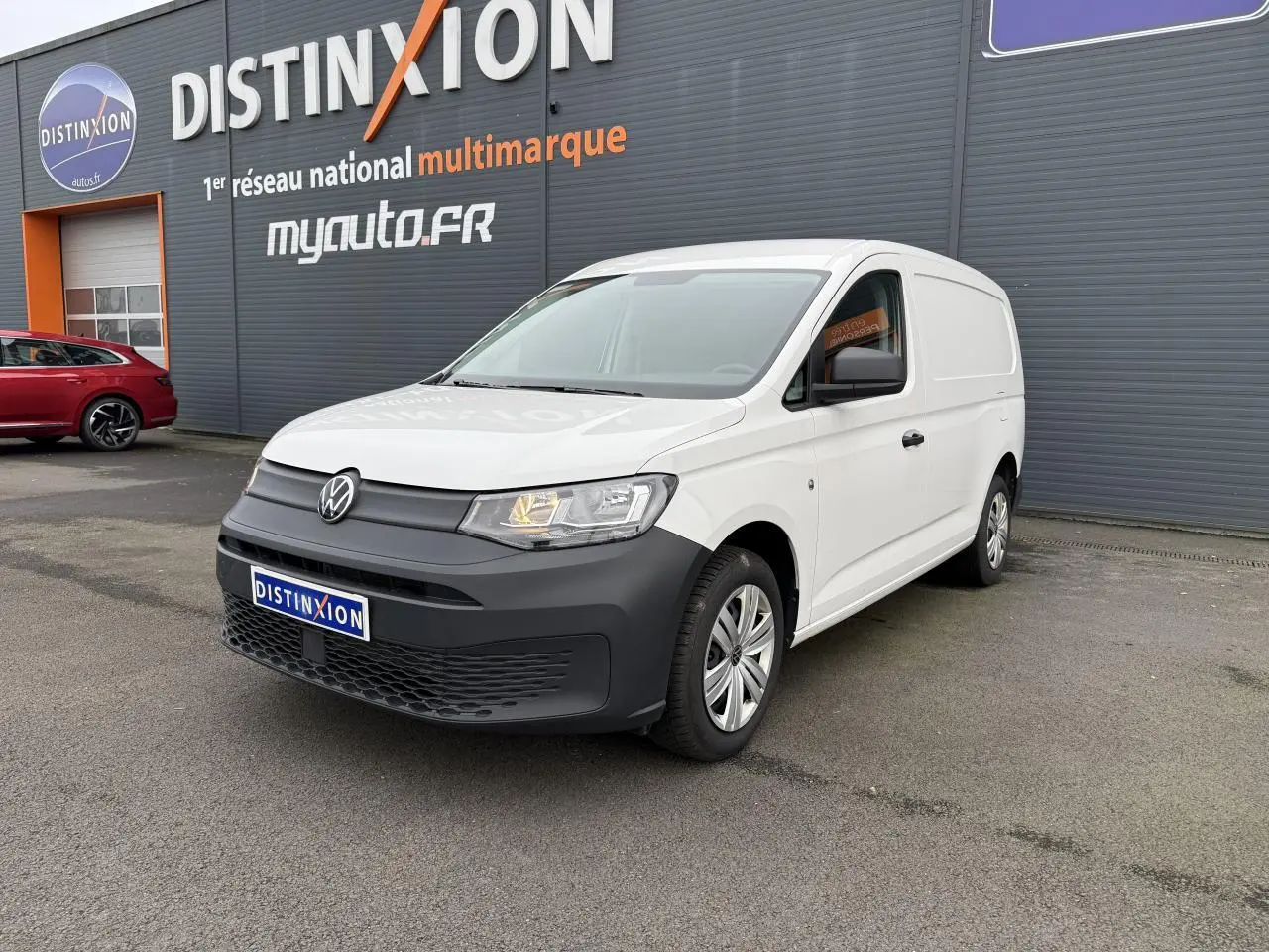 Volkswagen Caddy Maxi Cargo blanc candy en 3/4 avant droit avec pare-chocs noir mat et porte coulissante visible.
