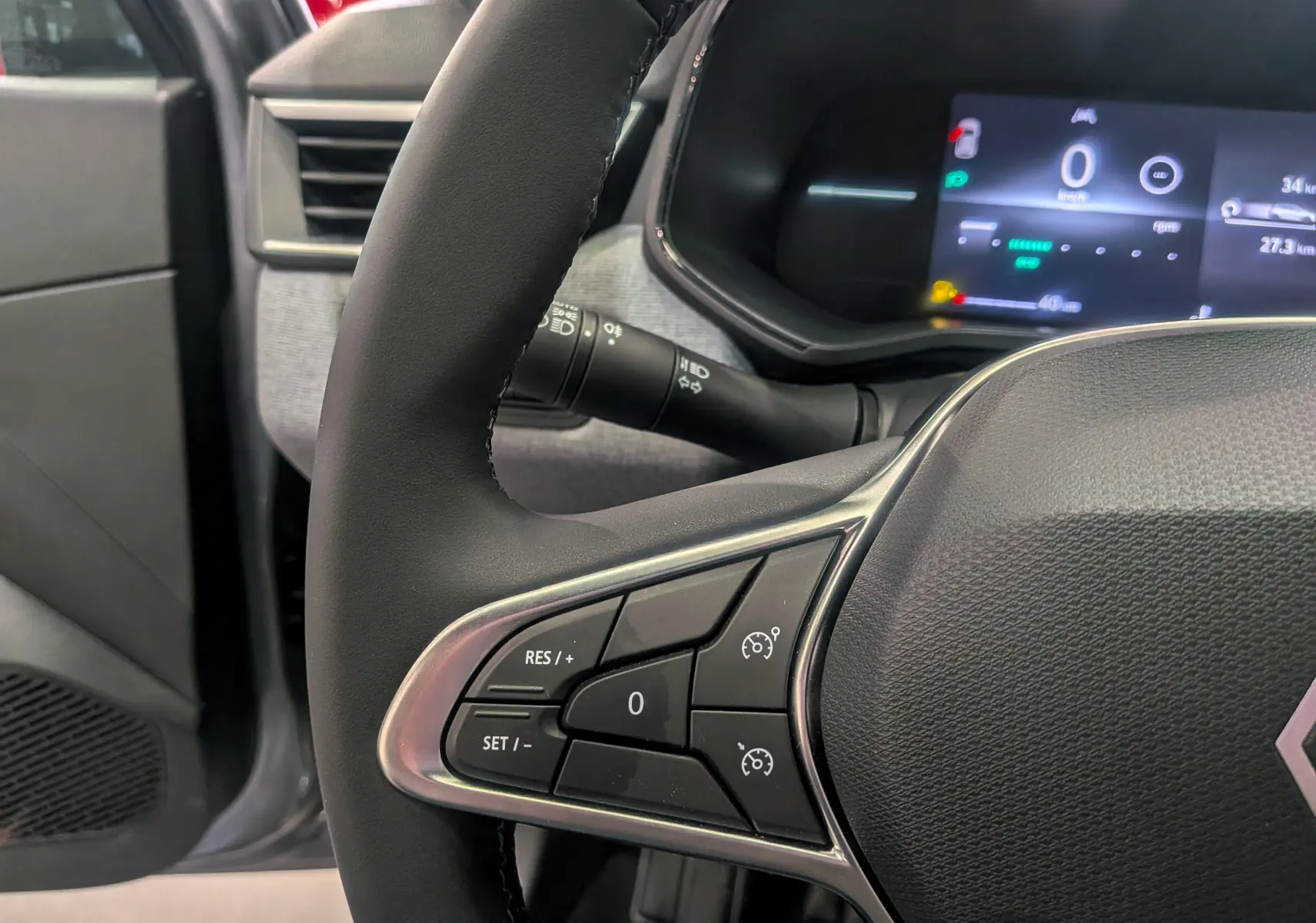 Gros plan sur le volant et le tableau de bord numérique de la Renault Clio V gris schiste, avec commandes au volant visibles.