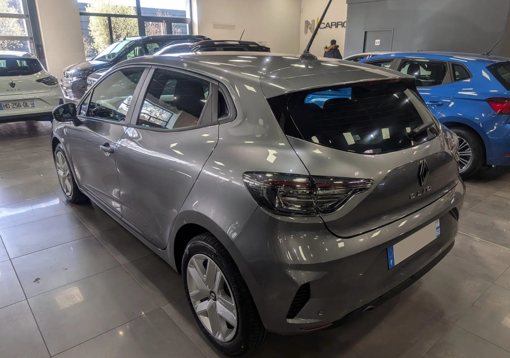 Vue 3/4 arrière droite d'une Renault Clio V gris schiste en concession, avec feux arrière LED et jantes spécifiques.