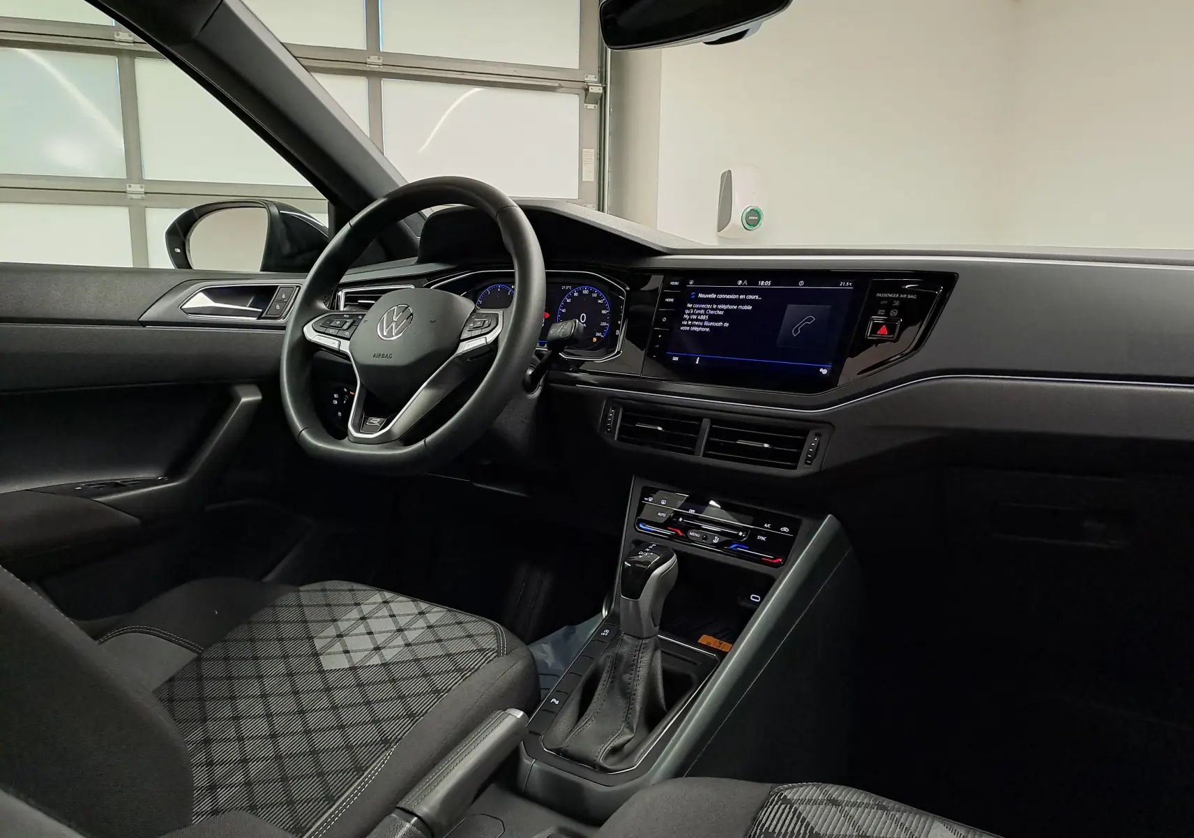 Vue intérieure côté conducteur du Volkswagen Taigo 2025, tableau de bord noir avec écran tactile et volant multifonctions.