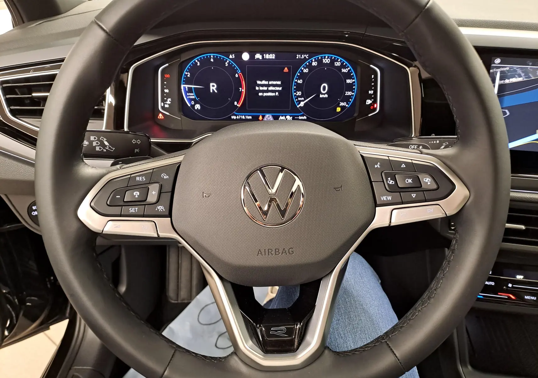 Vue rapprochée du volant cuir multifonctions avec logo Volkswagen et tableau de bord digital du Taigo noir intense nacré.
