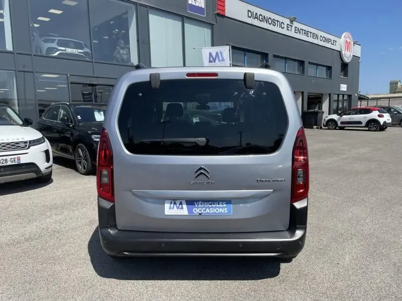 Vue arrière d'un Citroën Berlingo gris métal 2018 garé devant un centre de diagnostic et entretien complet.