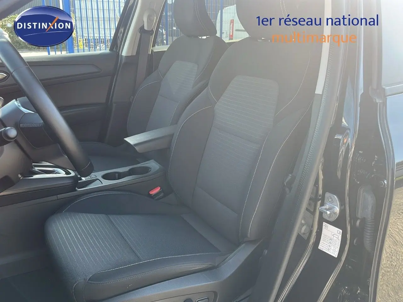 Vue intérieure côté conducteur du Renault Arkana noir métal 2023, sièges tissu gris et console centrale visible.