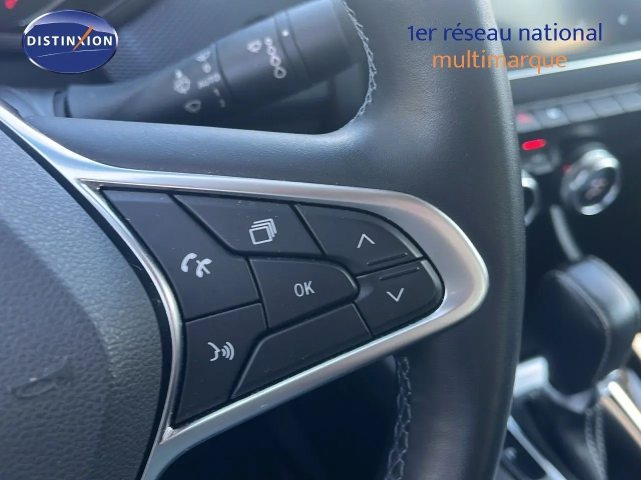 Gros plan sur les commandes au volant noir du Renault Arkana hybride 2023, avec détails chromés et console en arrière-plan.