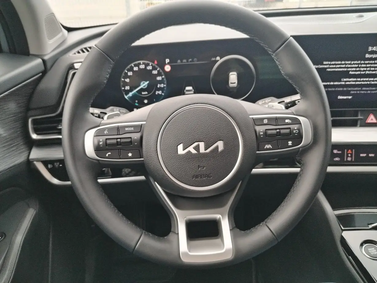 Vue rapprochée du volant noir du Kia Sportage 2025 avec commandes intégrées et tableau de bord numérique.