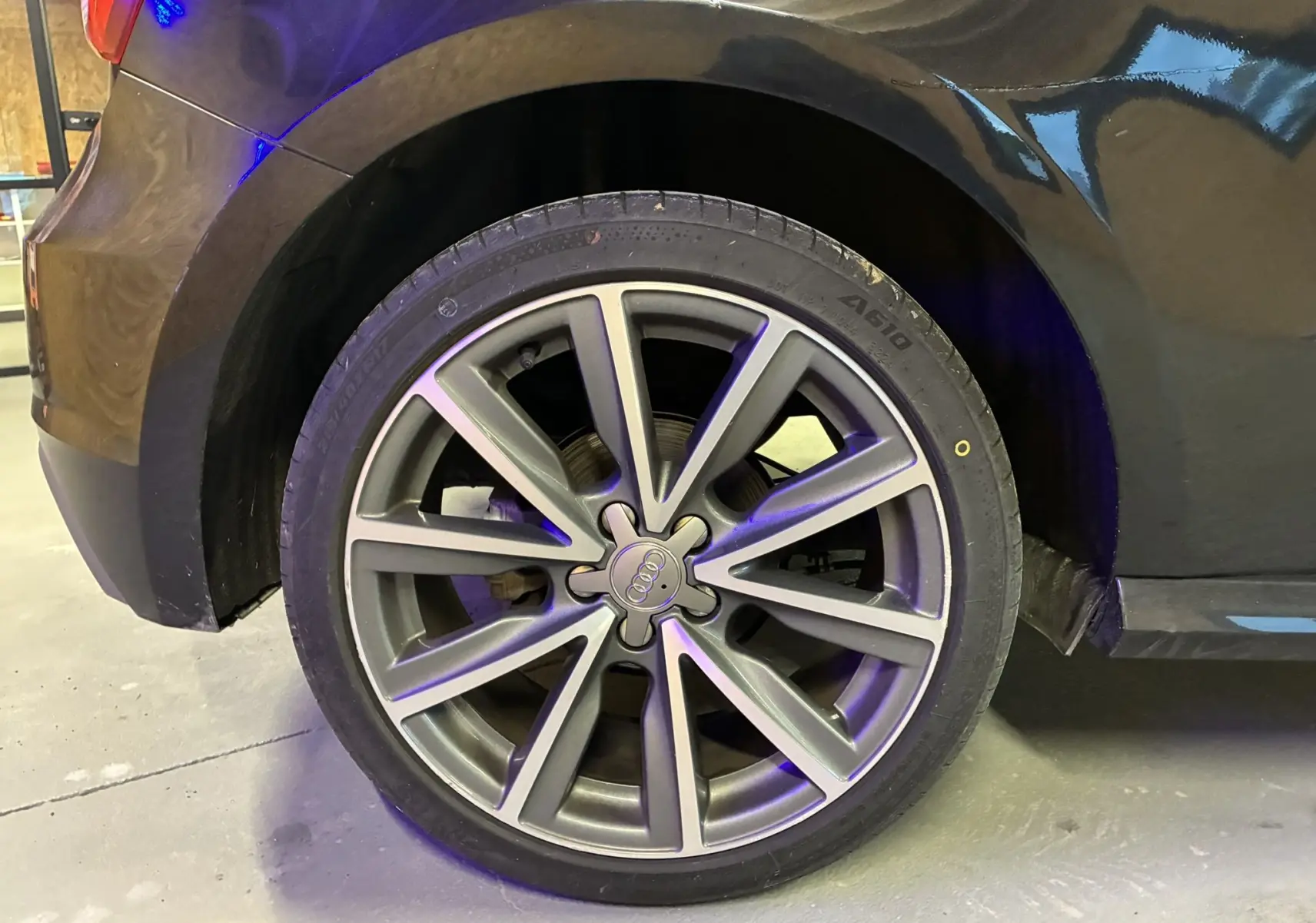 Gros plan sur la roue avant droite d’une Audi A1 noire de 2016, avec jante alliage S-Line à dix branches.