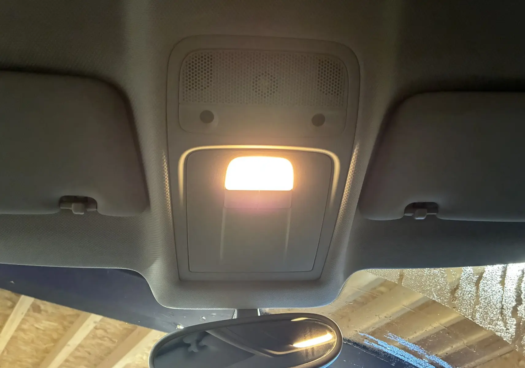 Vue intérieure centrée sur le plafonnier allumé et le rétroviseur intérieur d’une Audi A1 noire de 2016.