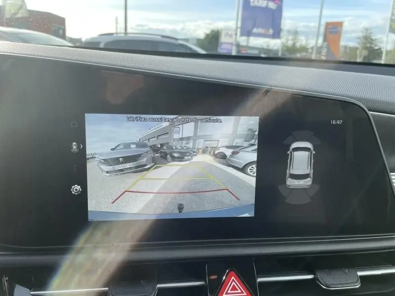 Vue écran intérieur montrant la caméra de recul d'un KIA Niro bleu métal en stationnement, avec guidage de trajectoire.