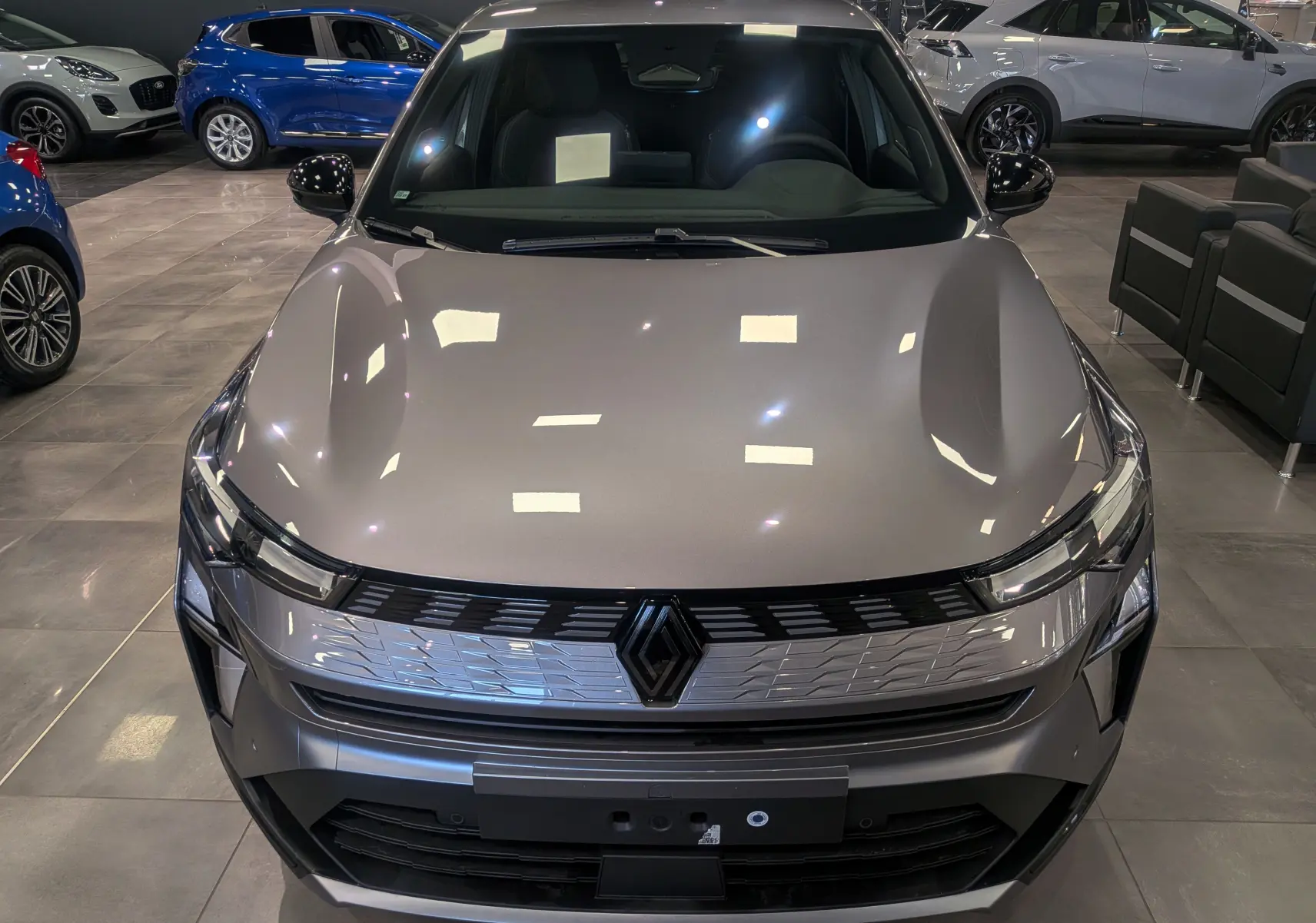 Vue avant d'une Renault SYMBIOZ E-TECH Full Hybrid gris Cassiopé, avec calandre chromée et logo central noir brillant.