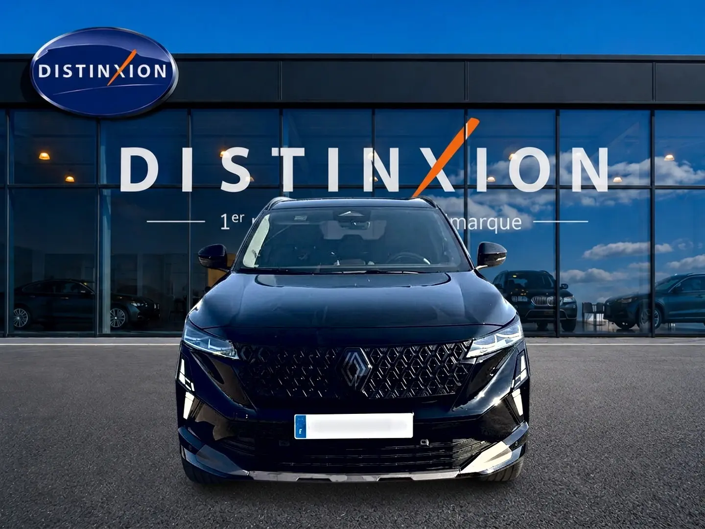 Vue frontale d'un Renault Austral noir avec calandre distinctive et phares LED, devant une vitrine Distinxion.