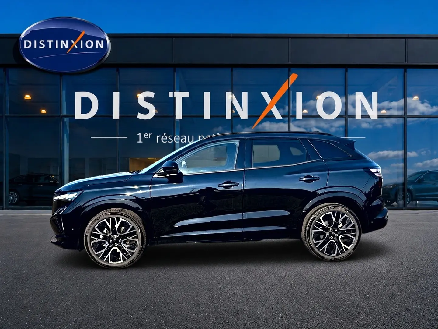 Profil droit d'un Renault Austral noir 2026 esprit alpine, avec jantes alu distinctives, stationné devant une vitrine Distinxion.