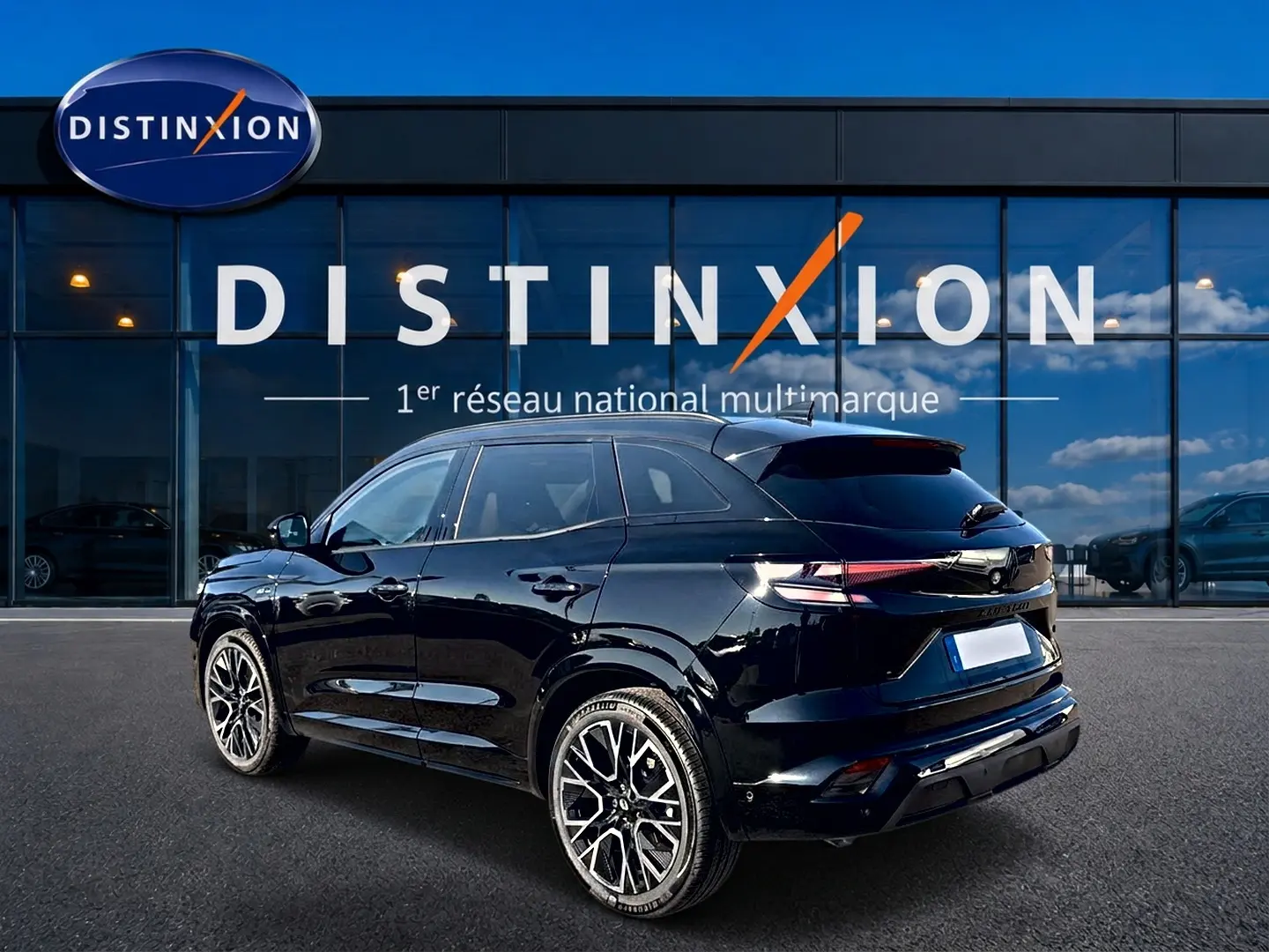 Vue 3/4 arrière droite d'un Renault Austral noir brillant avec jantes alu distinctives, devant une vitrine Distinxion.