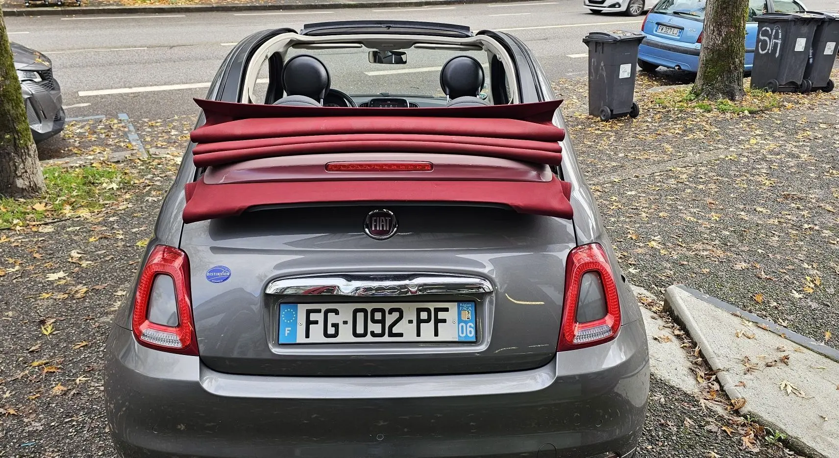 Gros plan sur le levier de vitesses manuel noir dans l'habitacle d'une Fiat 500C grise, avec commandes de climatisation visibles.