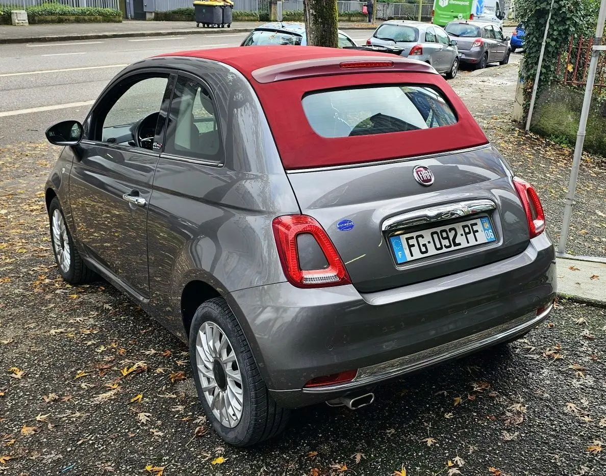 Fiat 500C gris métallisé vue 3/4 avant droit avec toit rouge et jantes alliage sur fond neutre.