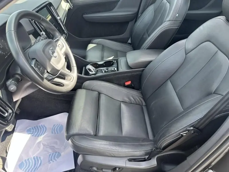 Vue intérieure côté conducteur du Volvo XC40 T4 gris foncé, montrant les sièges en cuir noir et la console centrale moderne.
