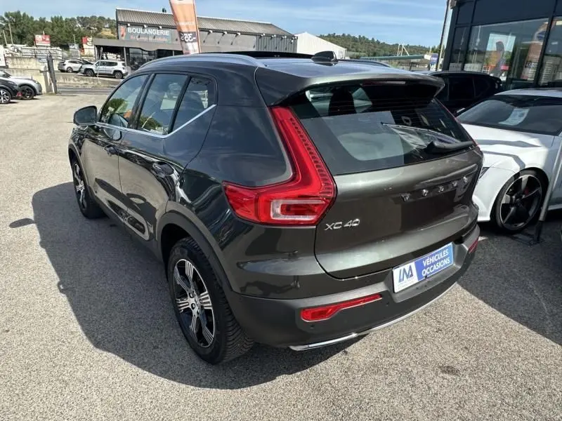 Vue 3/4 arrière droite d'un Volvo XC40 gris foncé métal 2019 avec feux arrière en forme de L et toit noir.