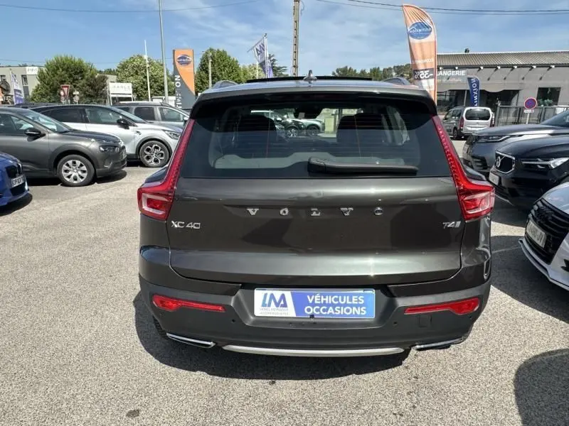 Vue arrière d'un Volvo XC40 T4 gris foncé métal, mettant en valeur ses feux arrière caractéristiques et son badge Inscription.