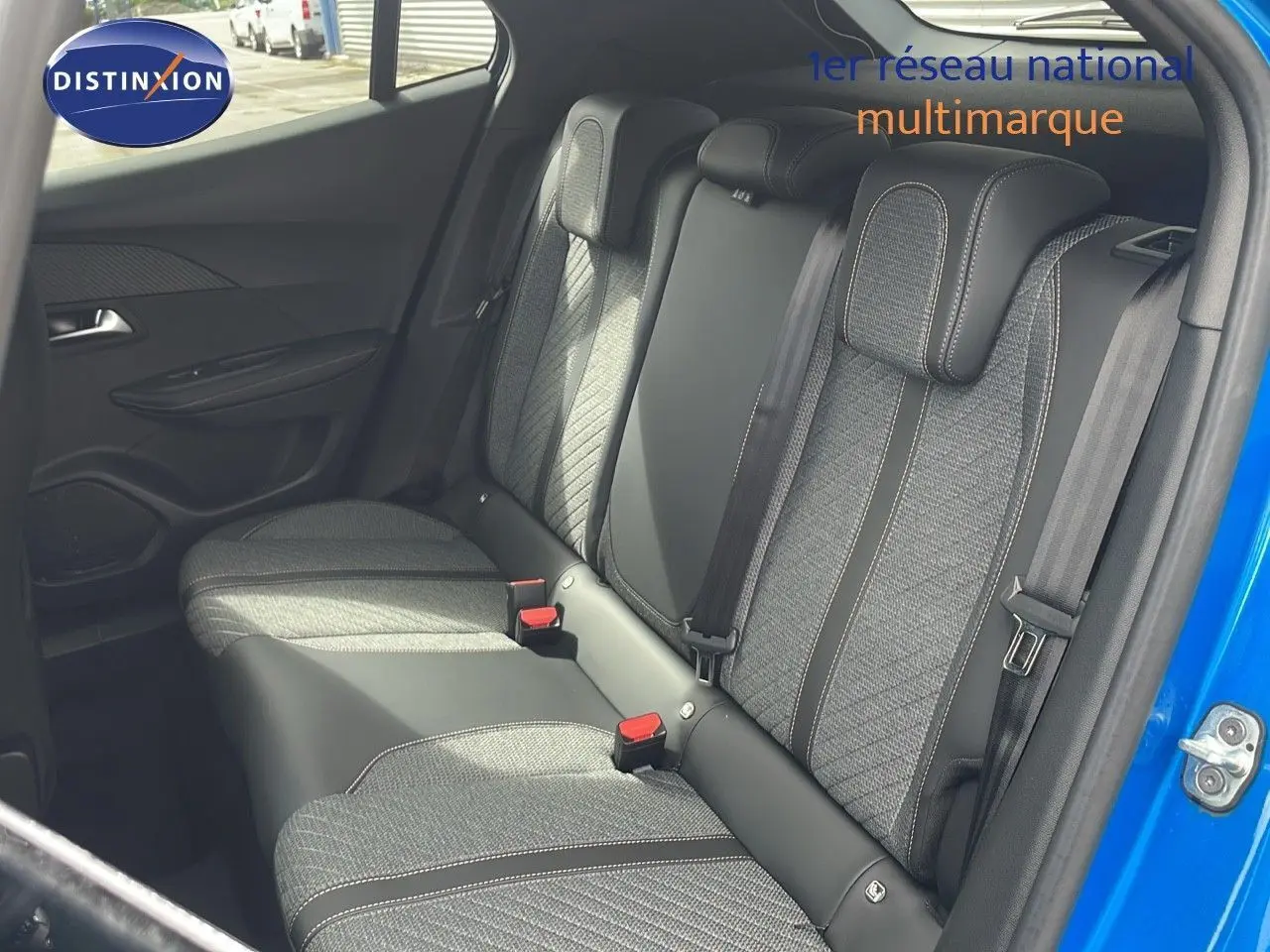 Vue intérieure sur la banquette arrière en tissu et cuir noir du Peugeot 2008 bleu Vertigo 2024, porte arrière droite ouverte.