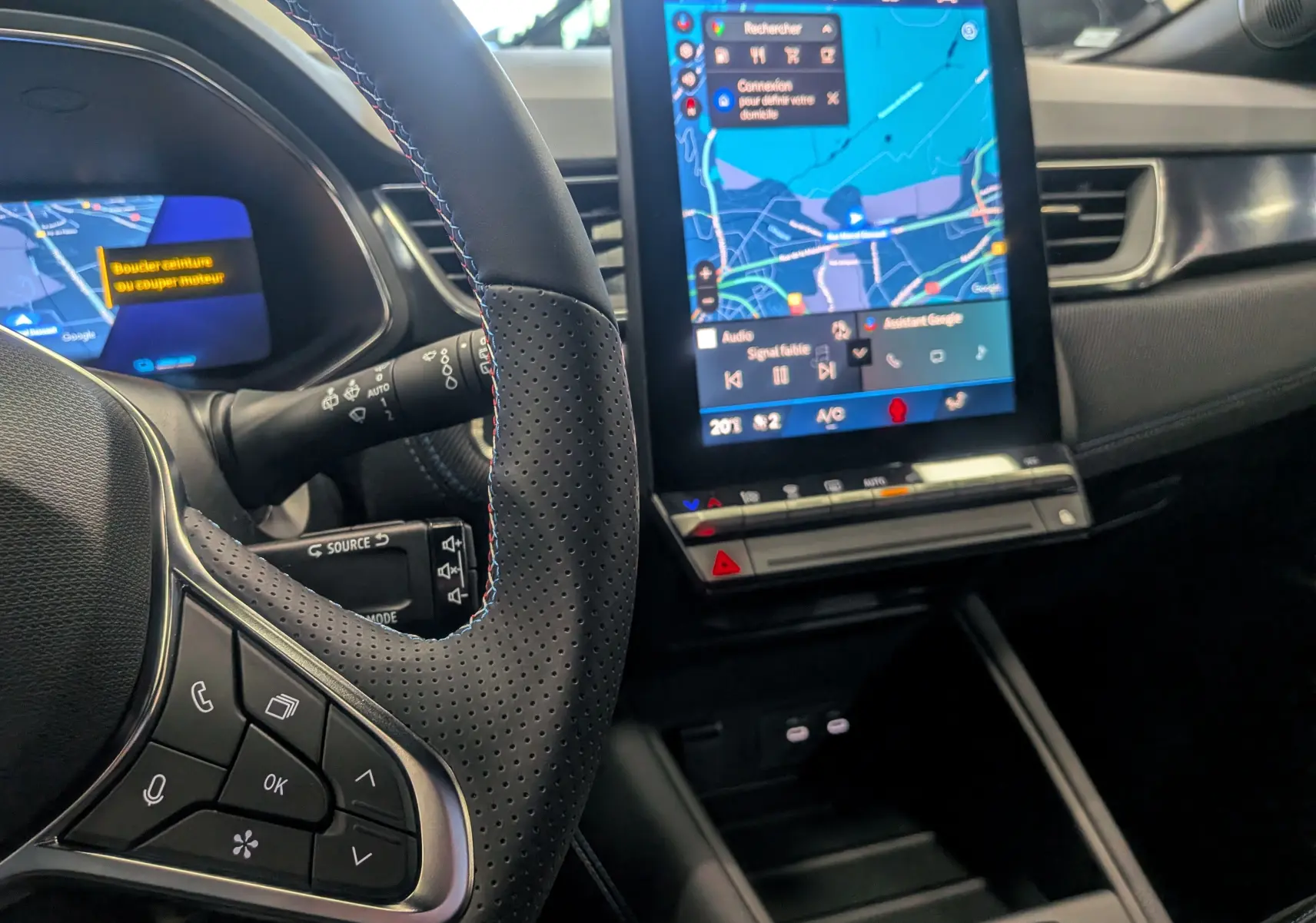 Vue intérieure rapprochée du volant en cuir noir et de l’écran tactile central affichant la navigation du Renault Symbioz E-Tech.