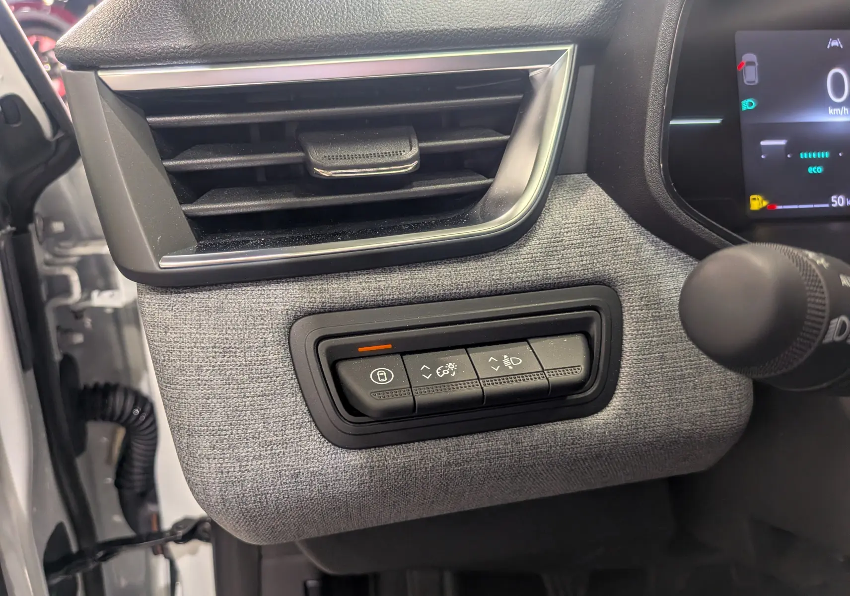 Détail intérieur côté gauche du tableau de bord gris tissu avec commandes d’éclairage sur Renault Clio V Blanc Glacier 2025.