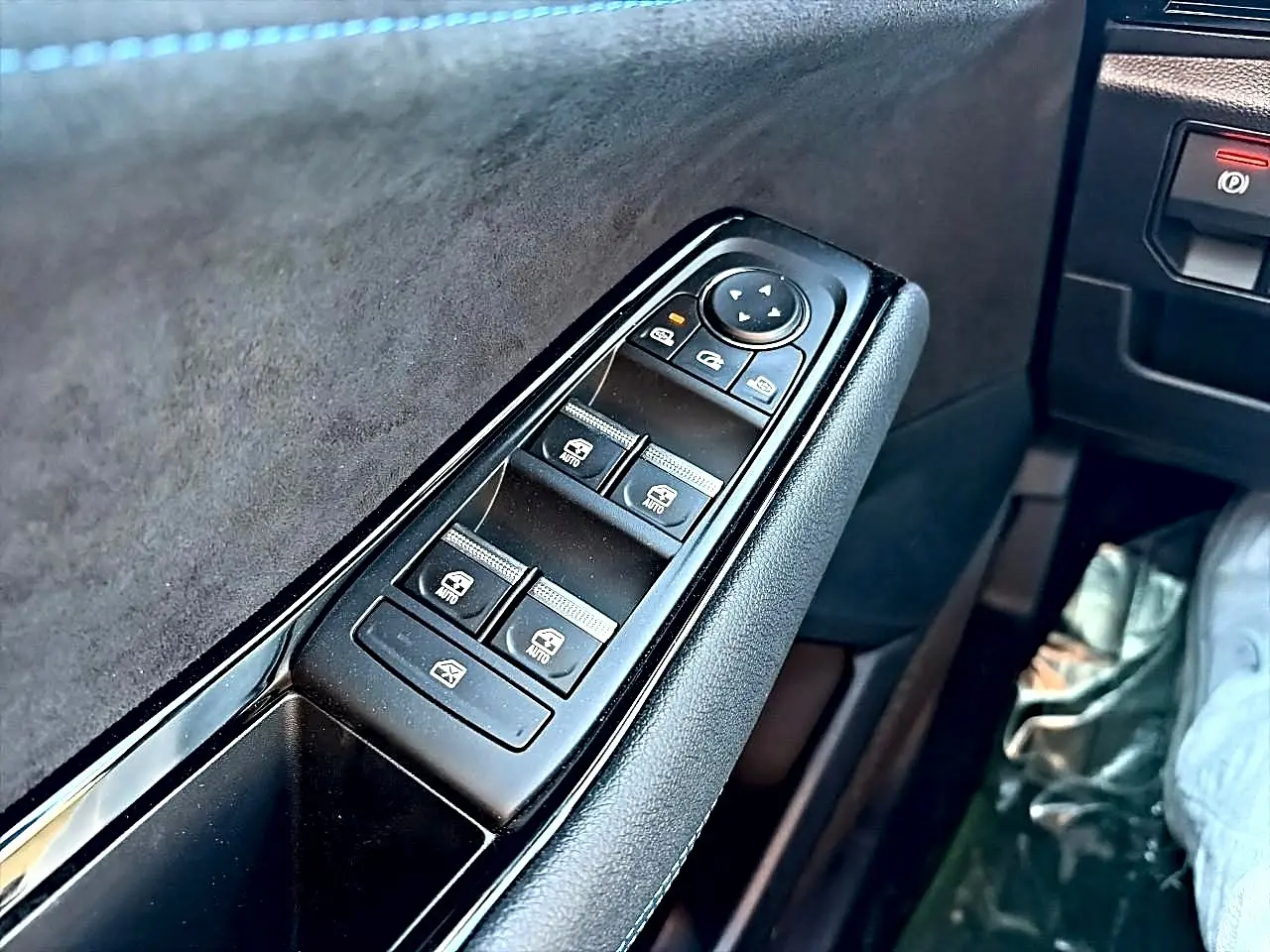 Gros plan sur la commande des vitres électriques côté conducteur du Renault Austral noir, avec revêtement en alcantara.