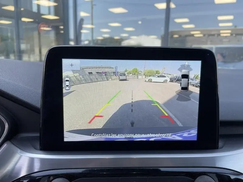 Écran de caméra de recul du Ford Kuga blanc 2020, vue arrière avec lignes d’aide au stationnement colorées.