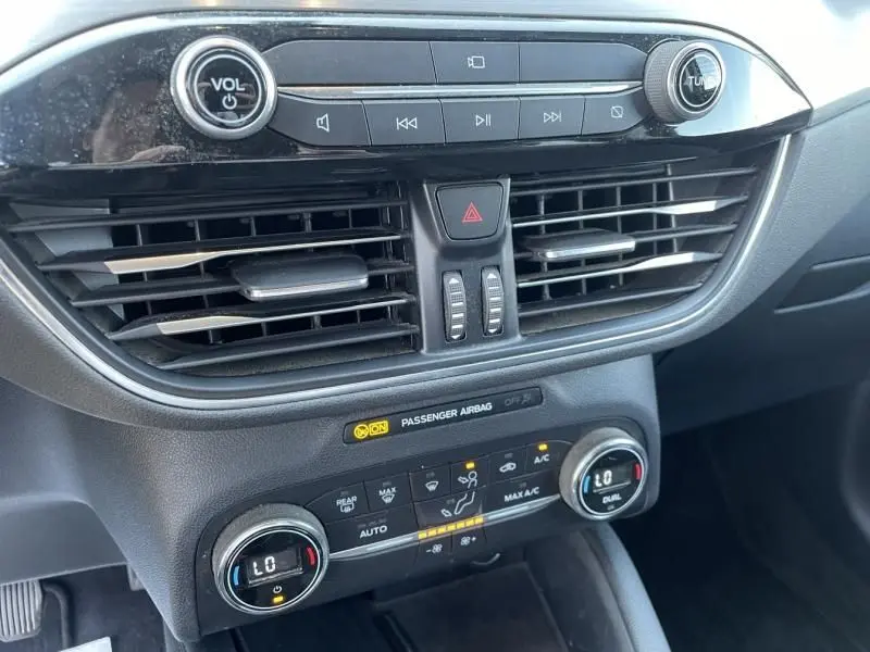 Vue rapprochée du tableau de bord noir du Ford Kuga 2020, mettant en valeur les commandes audio et climatisation digitale.