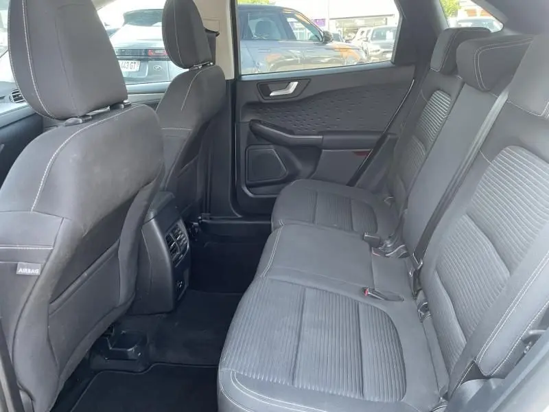 Vue intérieure arrière côté droit du Ford Kuga blanc 2020, montrant les sièges arrière en tissu noir et les portes.