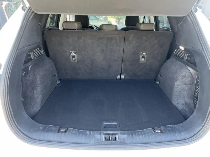 Coffre ouvert vu de l'arrière d'un Ford Kuga blanc 2020, montrant l'espace de chargement avec banquette arrière relevée.