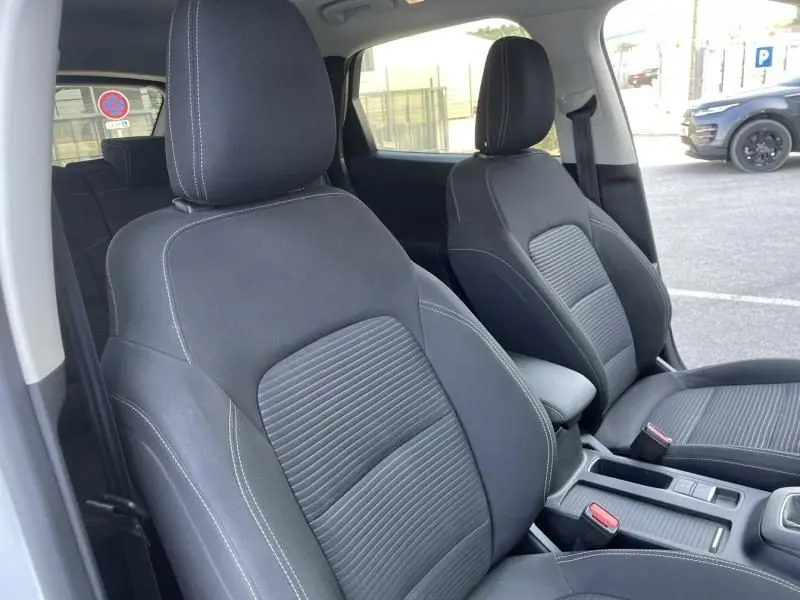 Intérieur du Ford Kuga 2020 blanc, vue côté gauche sur les sièges avant noirs avec surpiqûres blanches et console centrale.