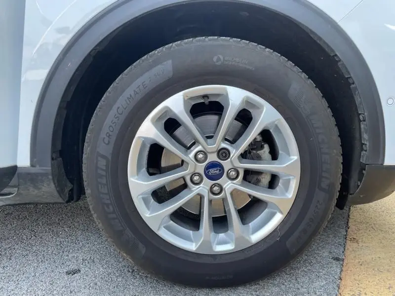 Gros plan sur la roue avant gauche du Ford Kuga blanc 2020, avec jante alliage et pneu Michelin CrossClimate SUV.