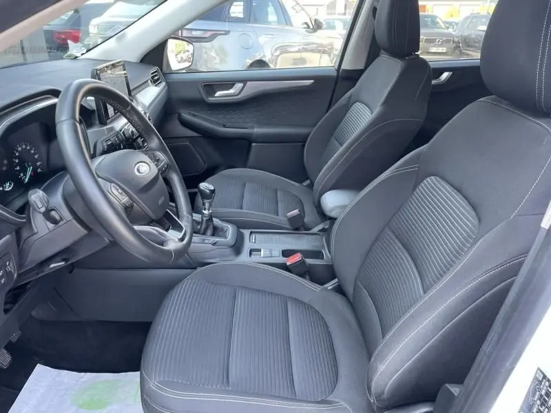Intérieur avant droit du Ford Kuga blanc 2020, montrant les sièges noirs, volant et levier de vitesse manuel.