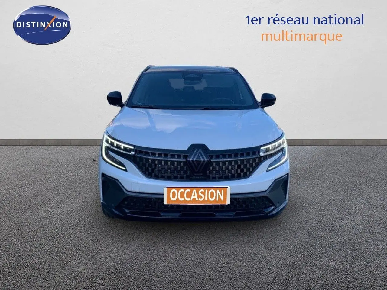 Vue avant d'un Renault Austral blanc métal avec toit noir, phares LED allumés et calandre noire distinctive.