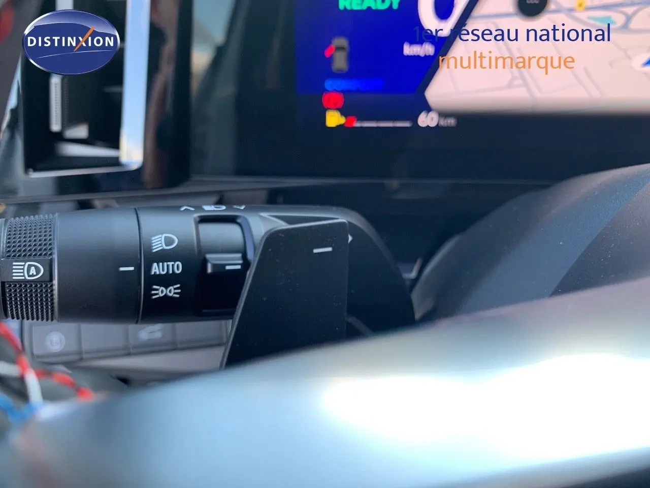 Gros plan sur la commande des phares et l'écran digital du tableau de bord du Renault Austral blanc métal 2024.