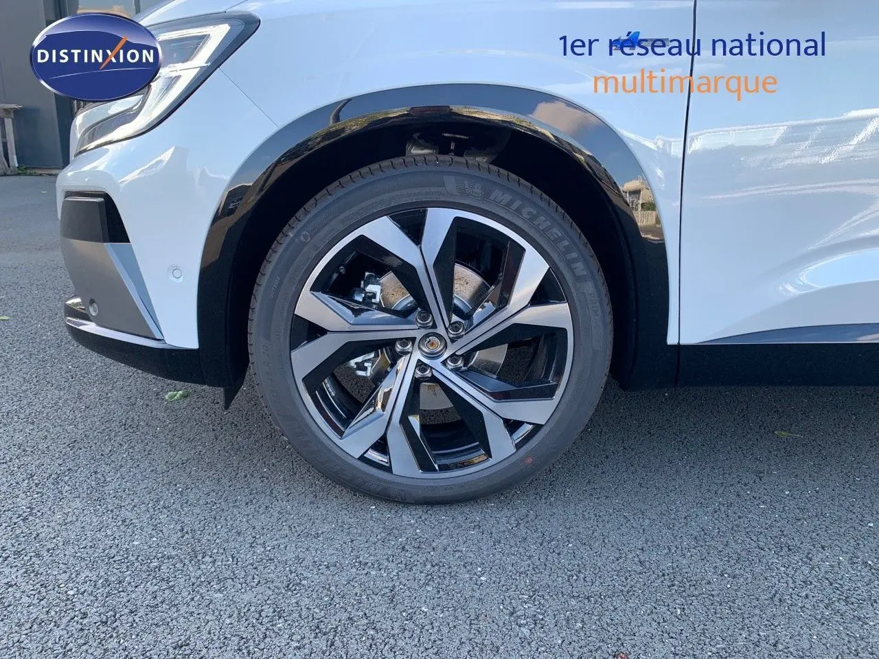 Gros plan sur la roue avant gauche du Renault Austral blanc métal avec jante alliage noire et toit noir visible.