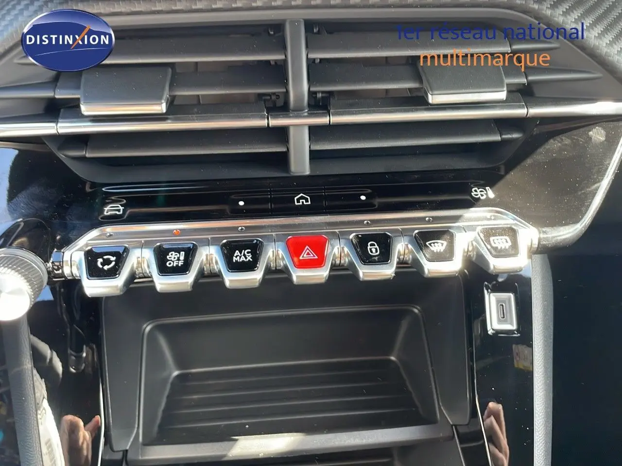 Gros plan sur la console centrale du Peugeot 2008 rouge Elixir Metal, montrant les commandes climatisation et boutons fonctionnels.