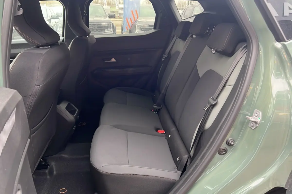 Vue côté droit sur l'intérieur arrière du Dacia Duster 2025 kaki lichen, montrant les sièges en tissu noir et gris.