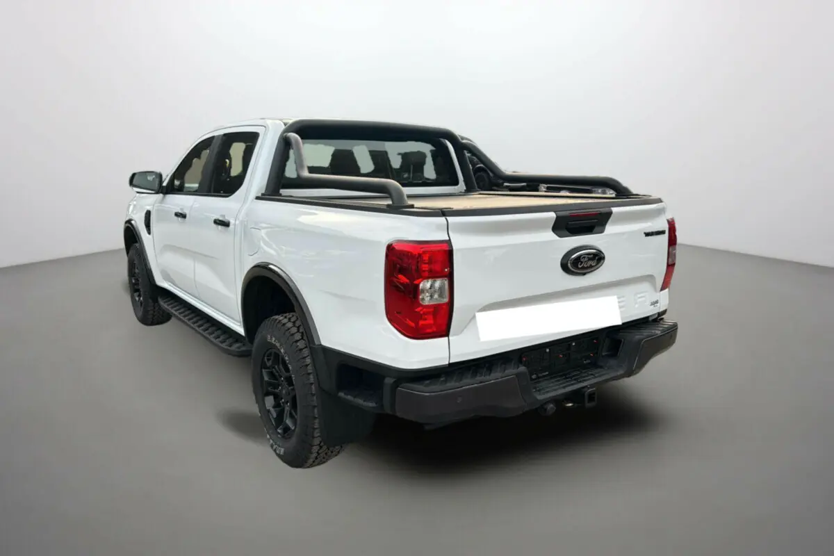 Ford Ranger blanc glacier en 3/4 arrière droit avec arceaux noirs et benne couverte sur fond neutre.