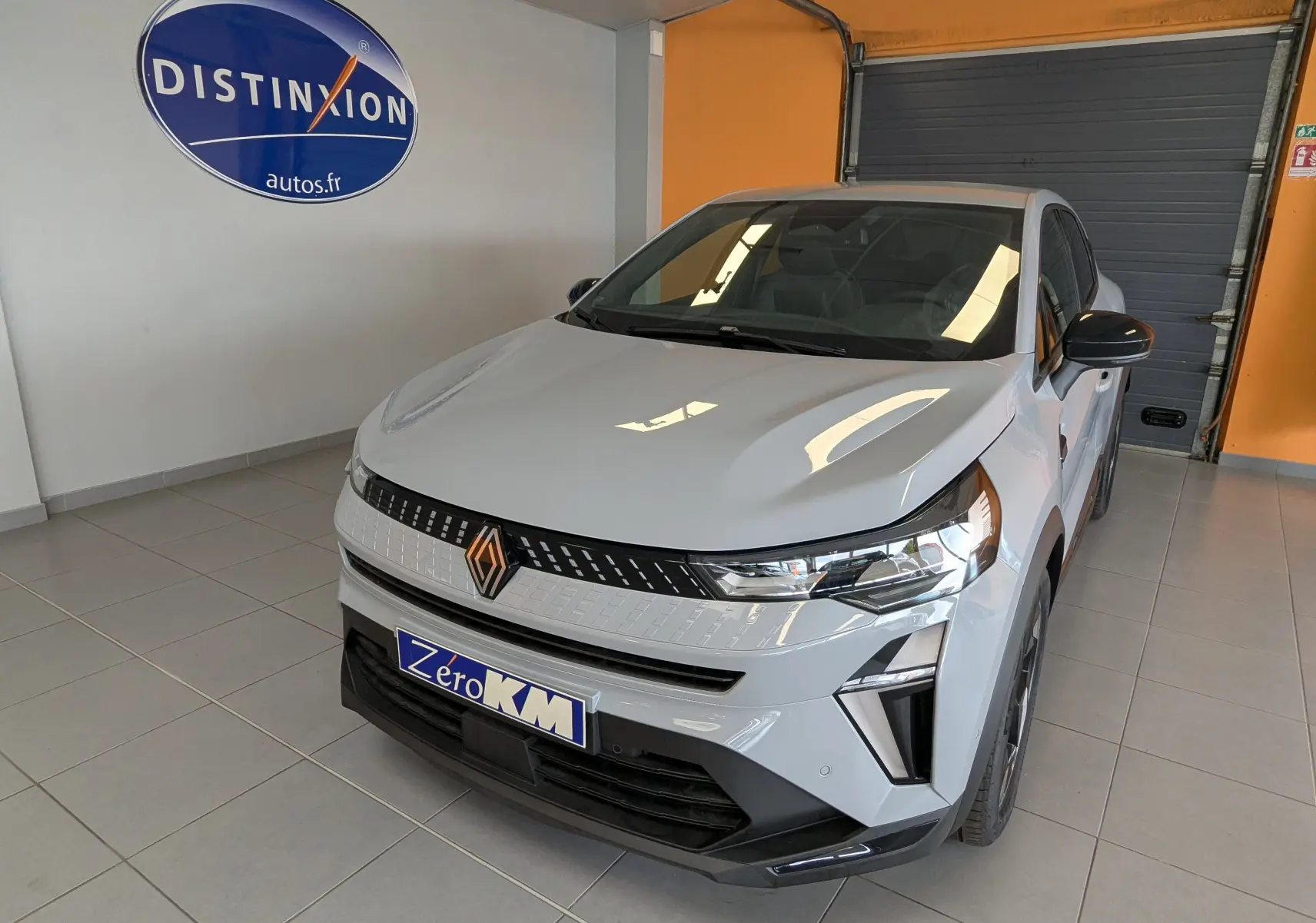 Vue 3/4 avant d'un Renault Captur 2025 gris zinc avec calandre moderne et phares LED dans un showroom.
