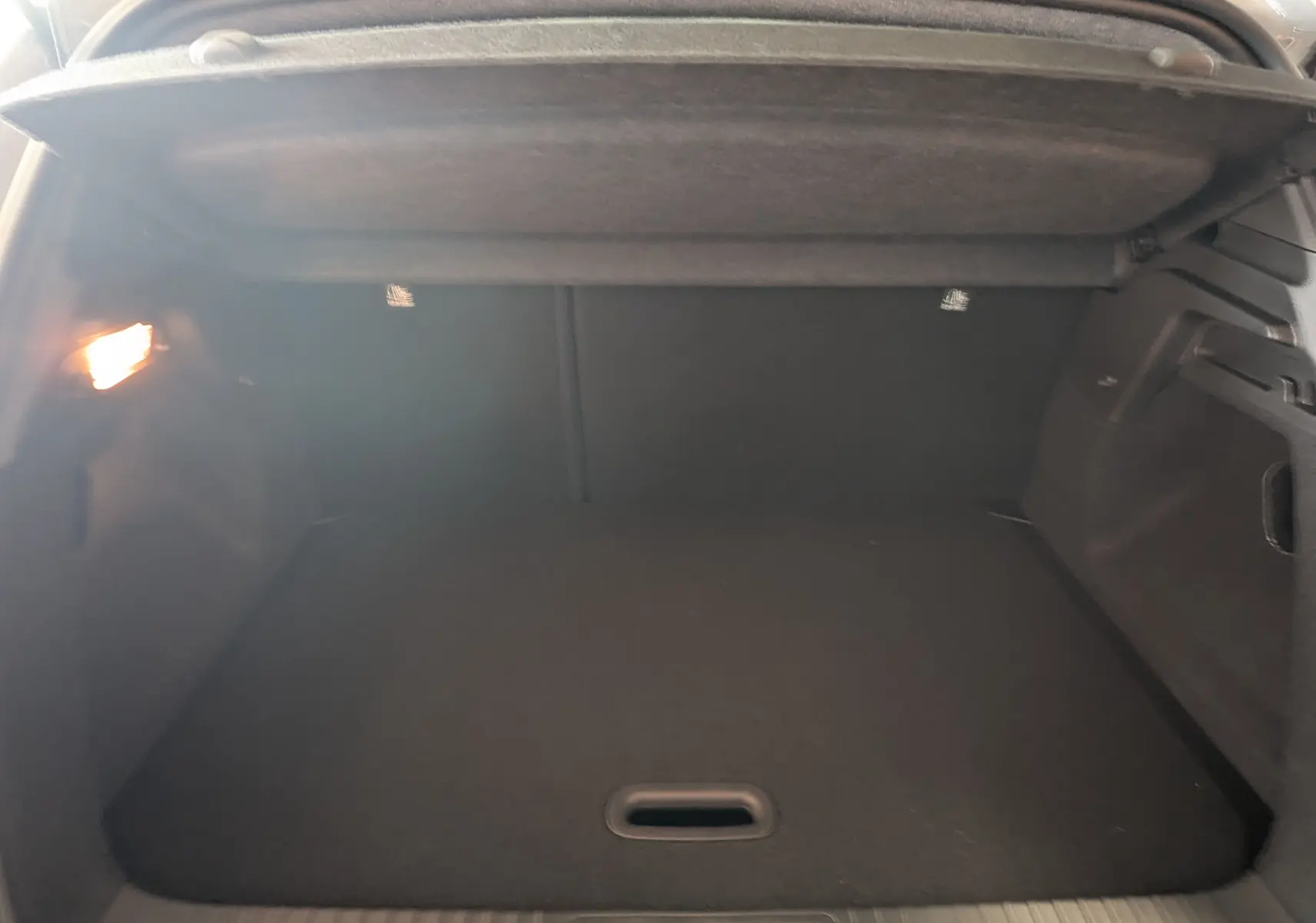 Coffre spacieux et éclairé du Renault Captur 2025 gris zinc, vue intérieure arrière avec cache-bagages relevé.