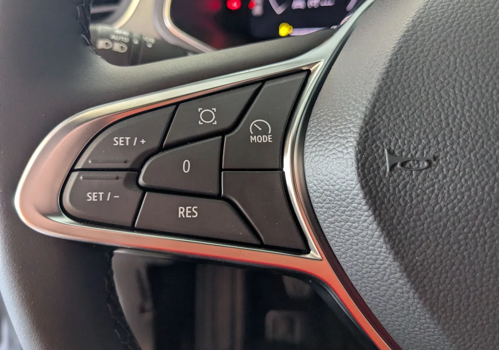 Gros plan sur les commandes de régulateur de vitesse au volant côté gauche du Renault Captur gris zinc 2025.