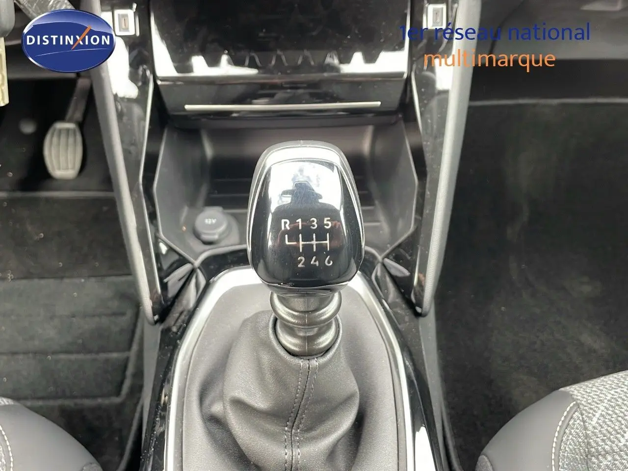 Le levier de vitesses manuel noir de la Peugeot 208 2024, vu de dessus dans l'habitacle sombre.