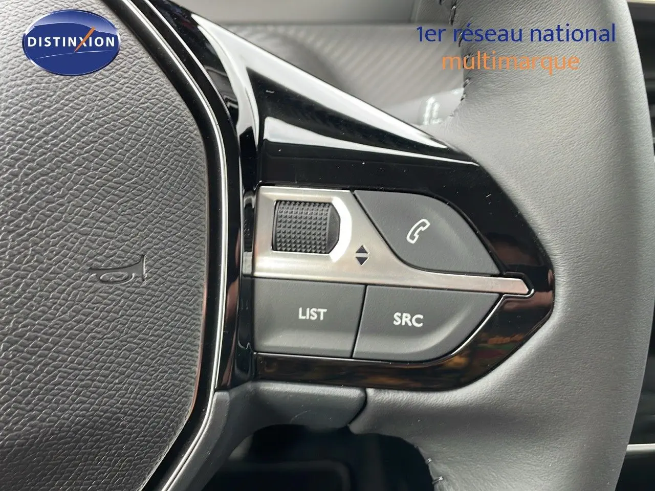 Gros plan sur les commandes gauche du volant en cuir gris d'une Peugeot 208 noire Perla Metal 2024.