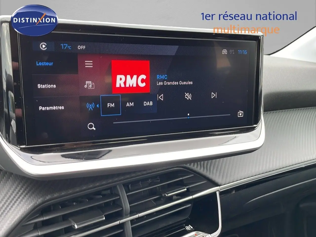 Écran tactile central affichant la radio RMC dans l'habitacle noir du Peugeot 208 1.2 PureTech 2024.