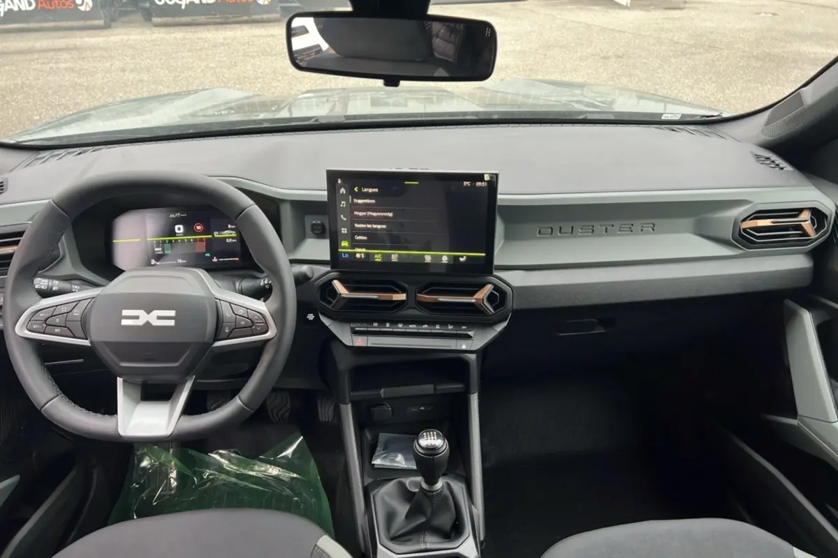 Vue intérieure du tableau de bord du Dacia Duster 2025 kaki lichen, avec volant multifonction et écran tactile central.